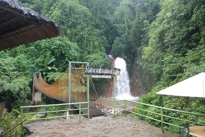 Pulangbato Falls met een hangbrug en een bord in een weelderig groene omgeving